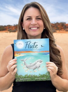 Jenni Goodman holding a copy of the picture book she illustrated - Flute. Flute is a dolphin from Monkey Mia.